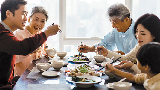 Parents, grandparents and a child eating in a bright room.