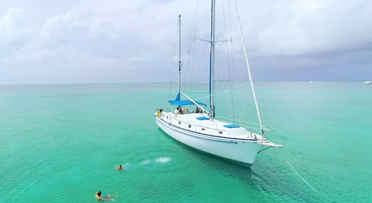 People swimming by sailboat