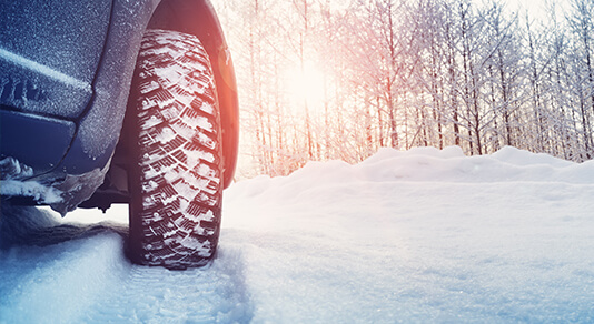 Car tires on winter road covered with snow