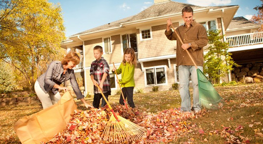 A family raking fall leaves in the backyard