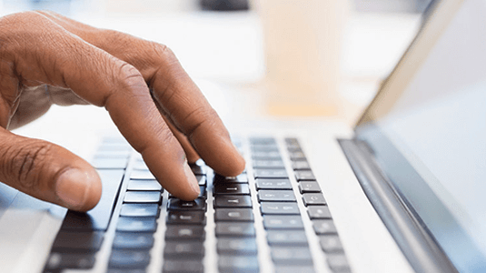 Close up of man typing on a computer keyboard