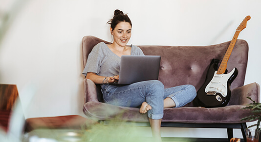 A young woman sitting on couch at home using laptop