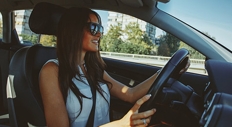 Young women driving a car wearing sunglasses.