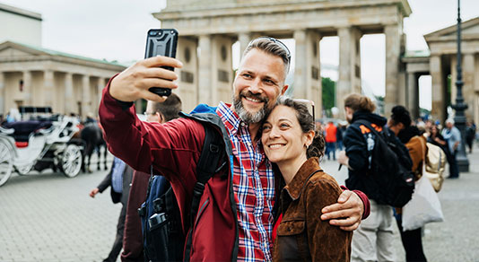 A mature couple taking a selfie in front of Brandenburg Gate in Berlin