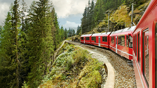 A red train crossing a bridge in the snowy Swiss mountains