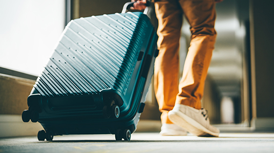 A man walks down the hotel corridor with luggage