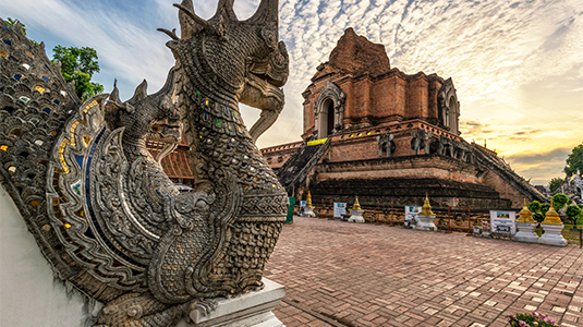 Ornate stone pagoda and dragon sculpture at sunrise.