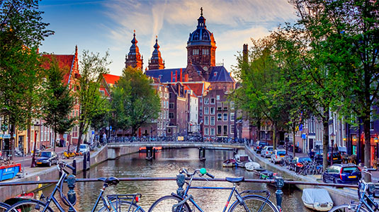 Bikes on a canal with a church in the distance.