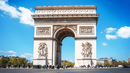 Pedestrians passing the Arc de Triomphe on a sunny day.