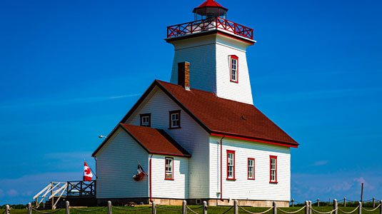 Red and white lighthouse under a sunny sky.
