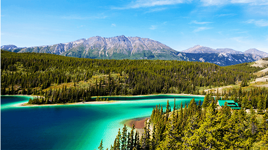 Panoramic view of turquoise Emerald Lake under a blue sky.