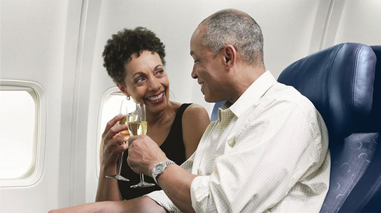 Couple toasting Champagne glasses on board of a plane.