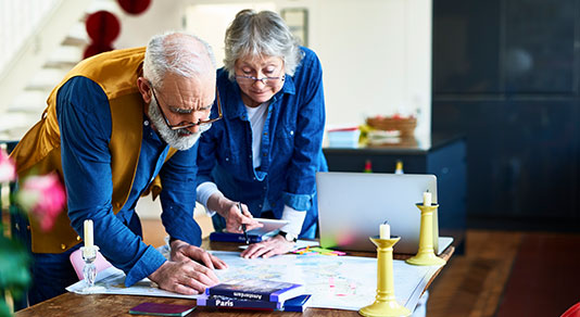 Senior travelers planning for a trip in living room.