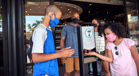 Family wearing masks and sanitizing their hands.
