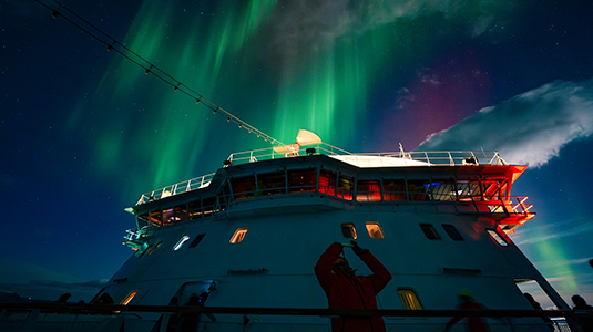Tourist photographing northern lights on boat
