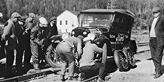 A black and white photo from 1920's showing motorists changing a tire