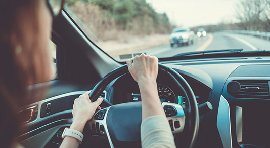 Woman driving a car with her hand on the steering wheel